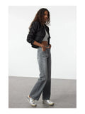 Femme portant un jean vintage taille haute évasé 100% coton avec un crop top et une veste noire.