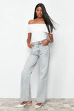 Femme portant un jean vintage taille haute évasé en coton et un top blanc décontracté, posant sur un fond neutre.