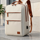 Sac à dos ordinateur portable blanc cassé avec détails marron, posé devant un immeuble moderne
