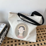 Sac fourre-tout en toile 'Milk Tea Happy Day' posé sur un banc en bois, anses noires visibles