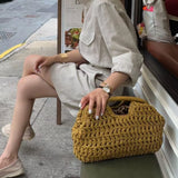Femme assise avec sac à main en paille tressée jaune moutarde