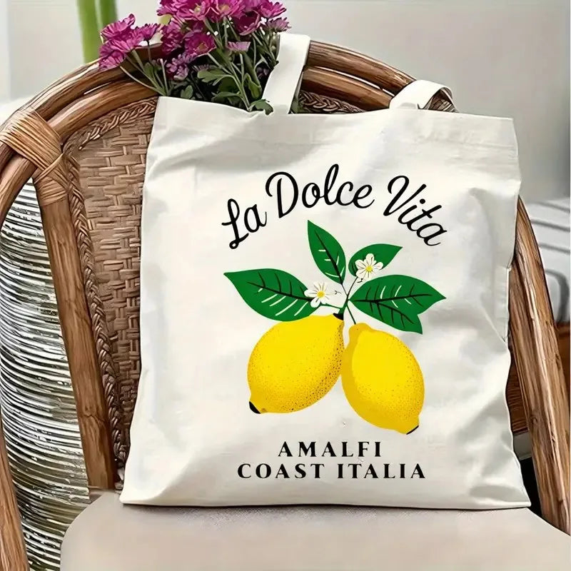 Sac fourre-tout en toile blanc avec motif La Dolce Vita et citrons, posé sur une chaise en rotin