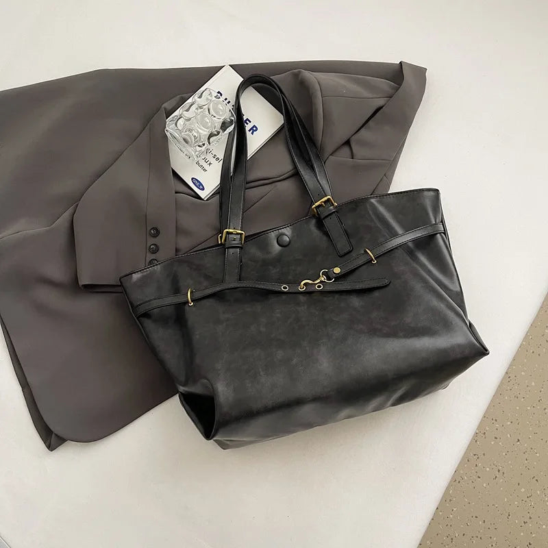 Sac fourre-tout rétro noir posé sur un blazer gris