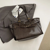 Sac fourre-tout rétro café posé sur un blazer gris