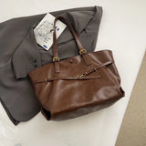 Sac fourre-tout rétro marron posé sur un blazer gris