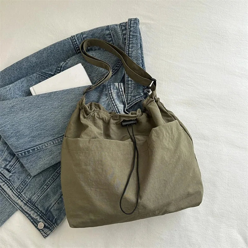 Sac bandoulière femme kaki avec cordon de serrage posé sur un jean