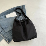 Sac bandoulière femme noir posé sur un jean, montrant sa forme souple